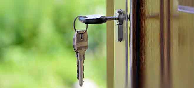 Photo of a key inserted in the lock of a green wooden door, used as a security blog header.