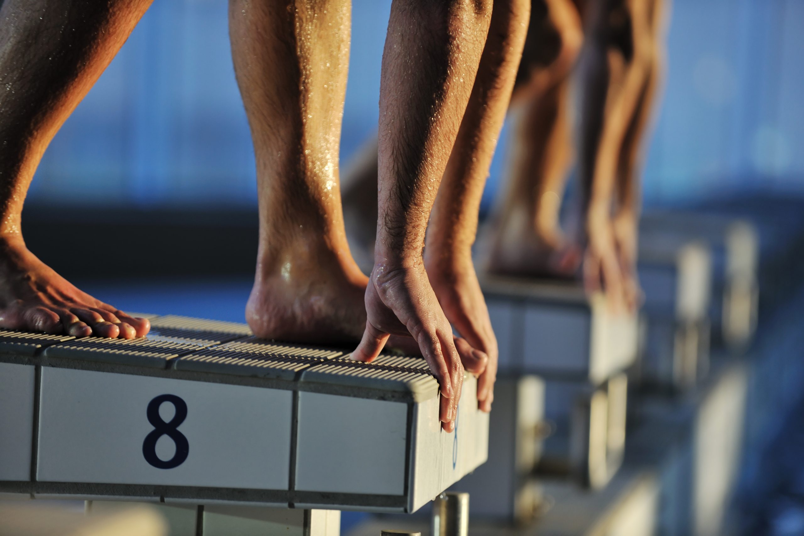 Close-up of runners' feet on a starting block numbered 8.