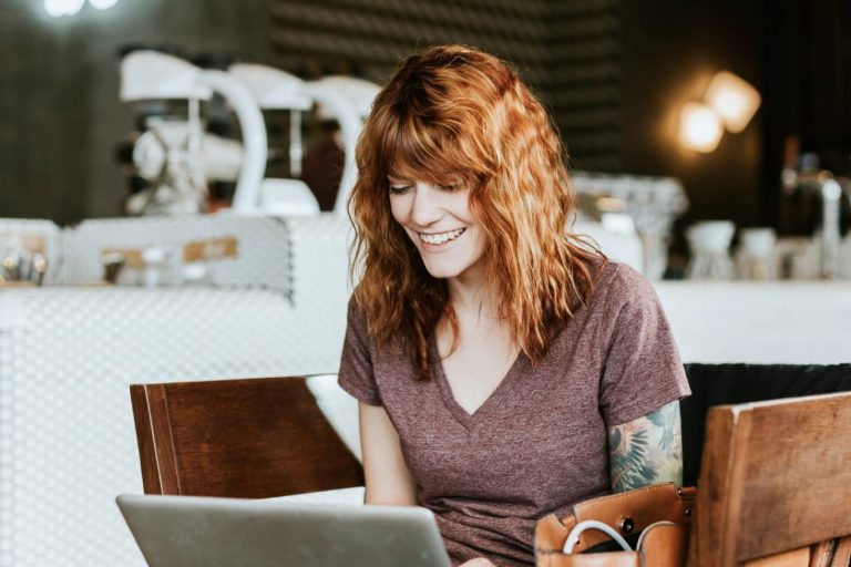 smiling-woman-on-laptop-in-cafe